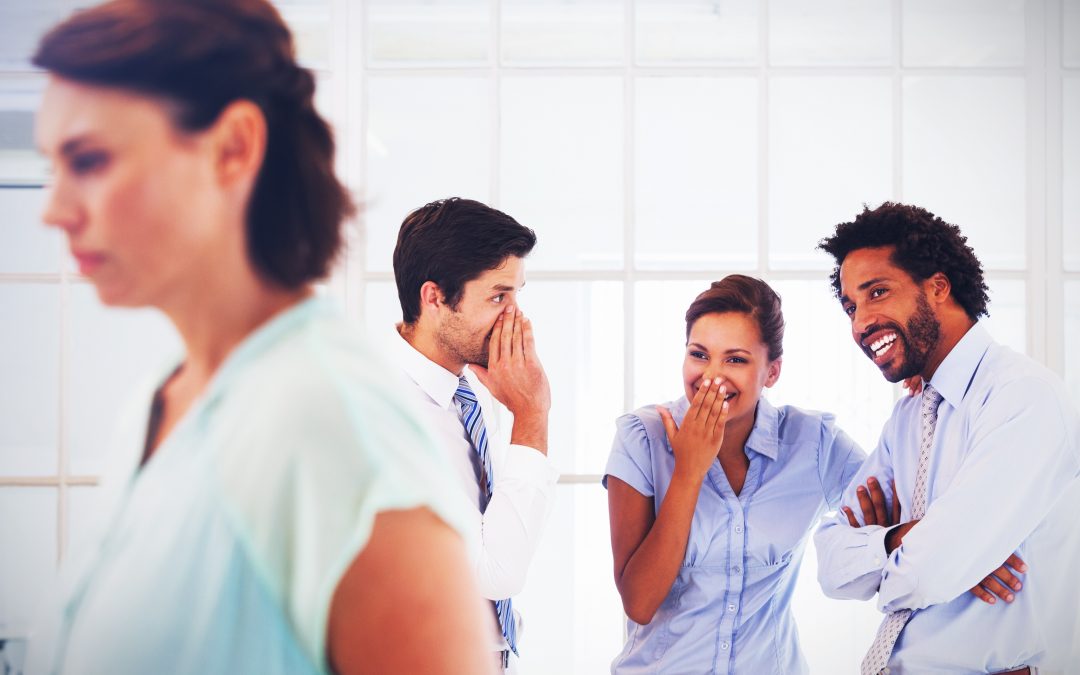 Colleagues gossiping with sad businesswoman in foreground